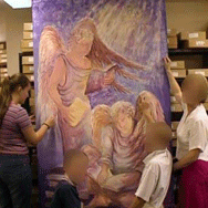 Students painting a large portrait canvas of an angel
